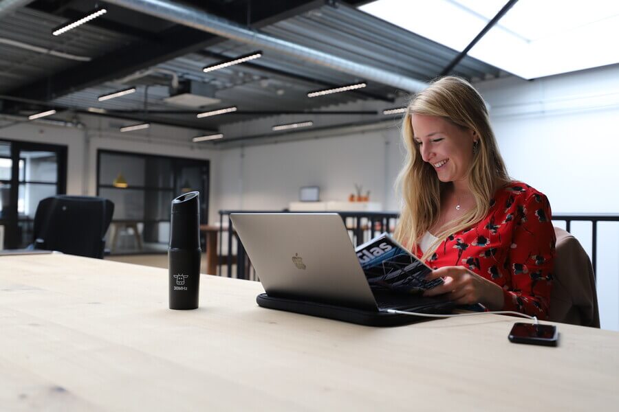 Woman reading Agri magazine behind her laptop in the office